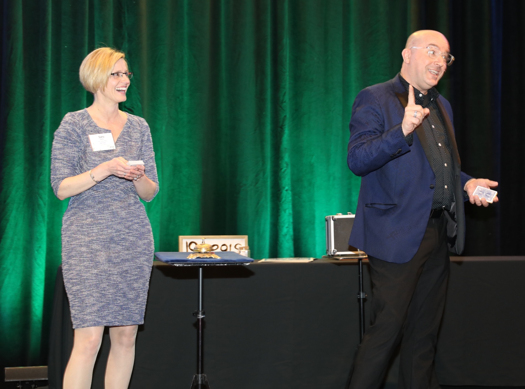Tim performing a card routine with a woman volunteer on stage