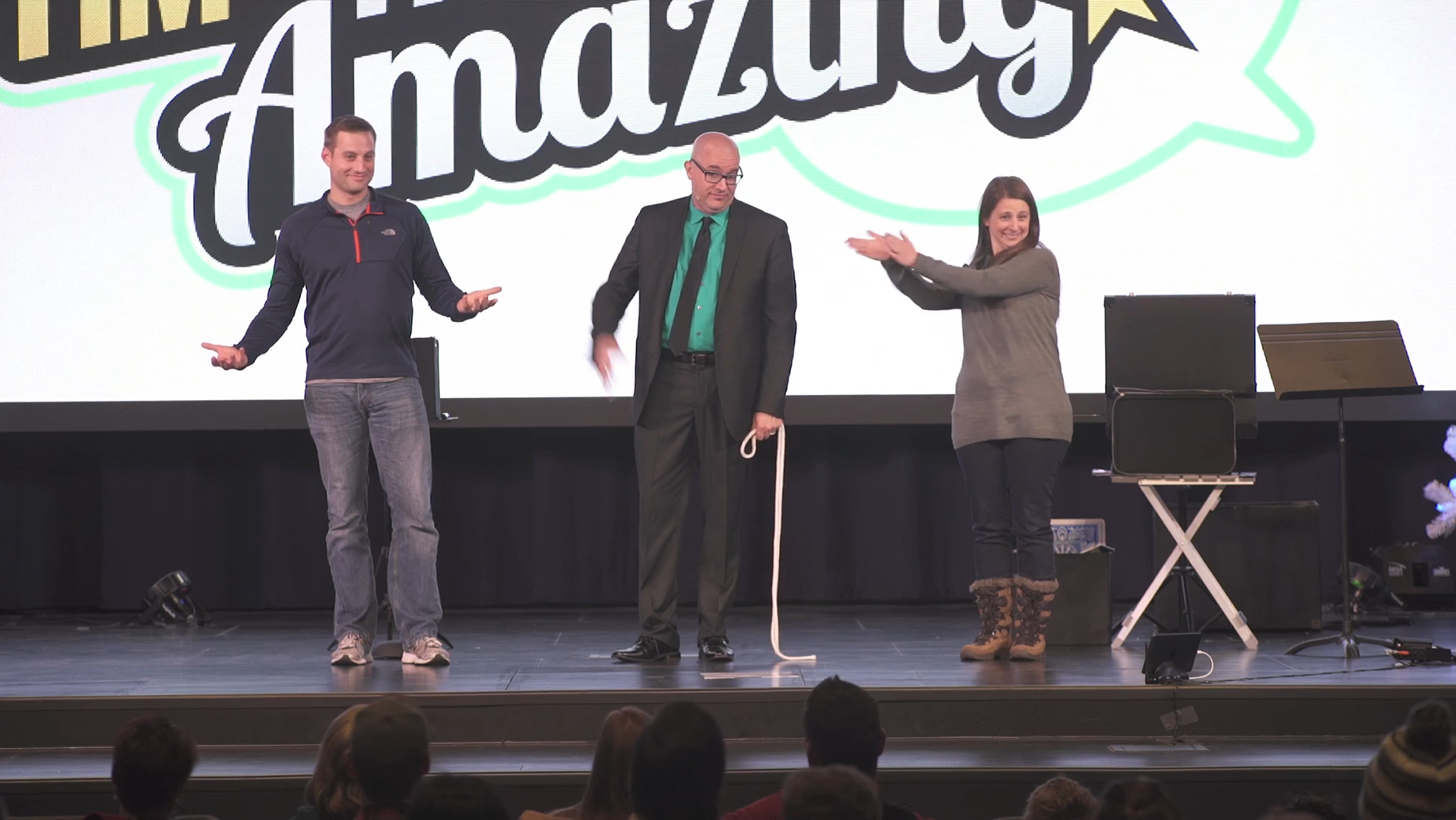 Tim on stage with a man and a woman volunteer during a rope routine