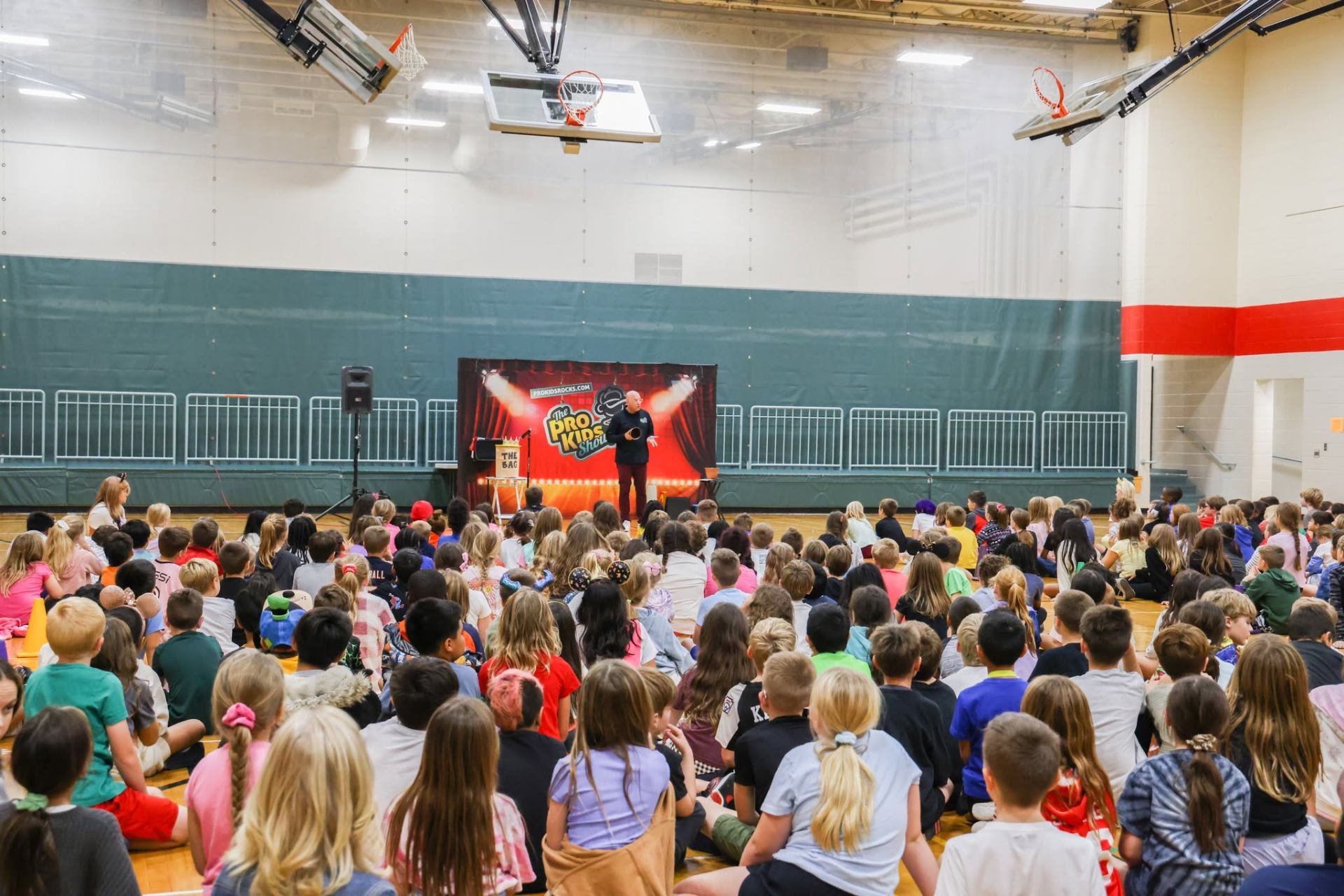 Students seated on a gymnasium floor watching The Pro-Kids Show