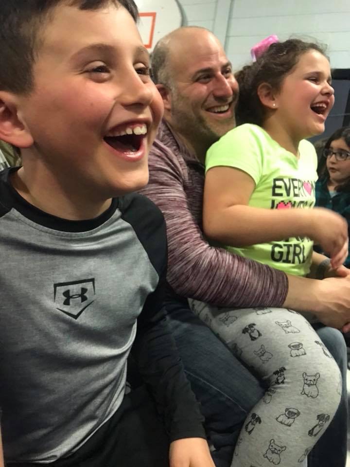 A dad and his two kids caught mid-laugh during Family Night