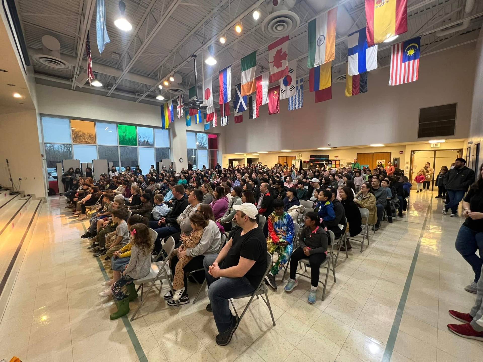 Packed family night audience with international flags overhead